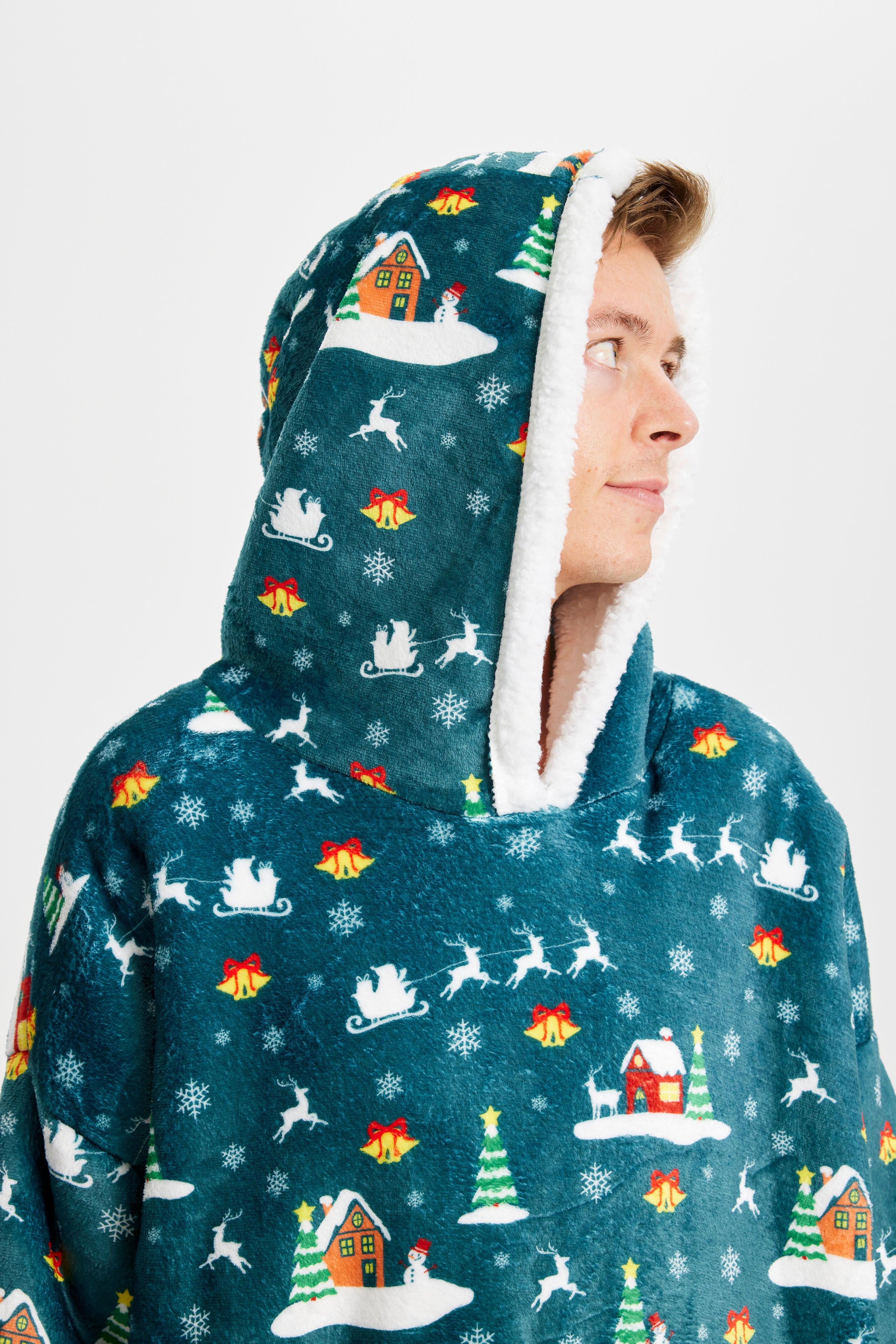 En mand med hætten over hovedet kigger til siden, mens han står i en blå julehoodie.